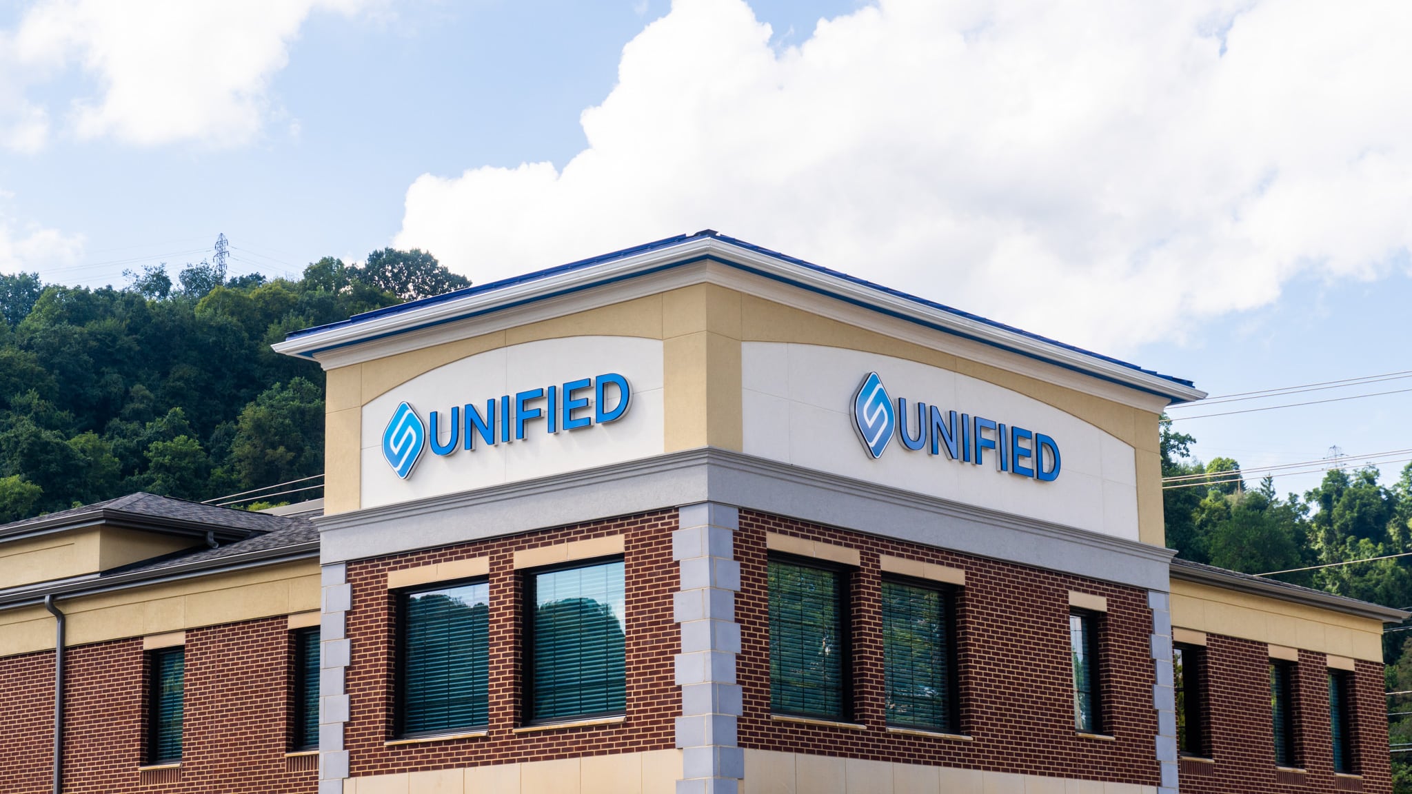 Corner view of Unified Bank Wheeling branch tower with blue standing seam metal roof, white fascia and shingle roofs by Kalkreuth