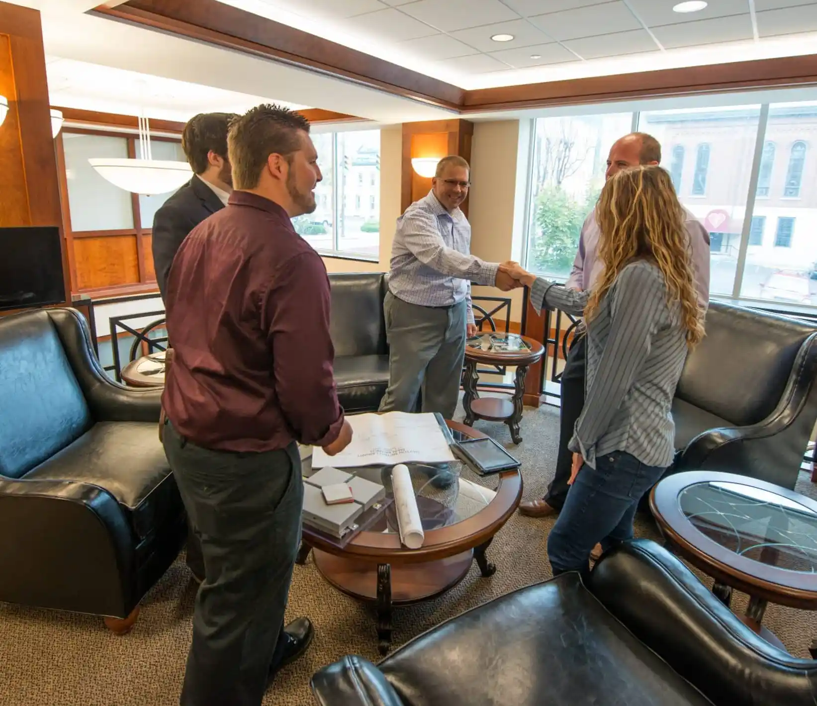 Kalkreuth management team members shaking hands over blueprints in an office lounge